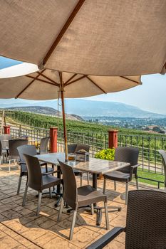 Street cafe tables under satin umbrellas with Okanagan valley overview on a foggy day
