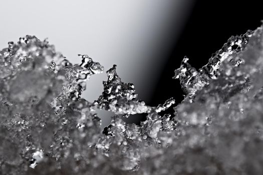 Thawing snow or frost, super macro close up image with an abstract background. Selective focus and soft black and white background. Microscopic detail
