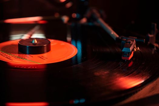 Needle detail on vinyl record on turntable, low light image with reflection