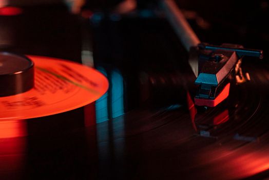 Needle detail on vinyl record on turntable, low light image with reflection