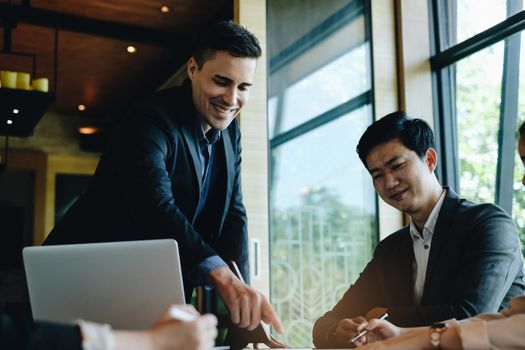 During a business meeting with colleagues, a company marketologist gives a presentation about market plan and investment and pointing at paperwork.