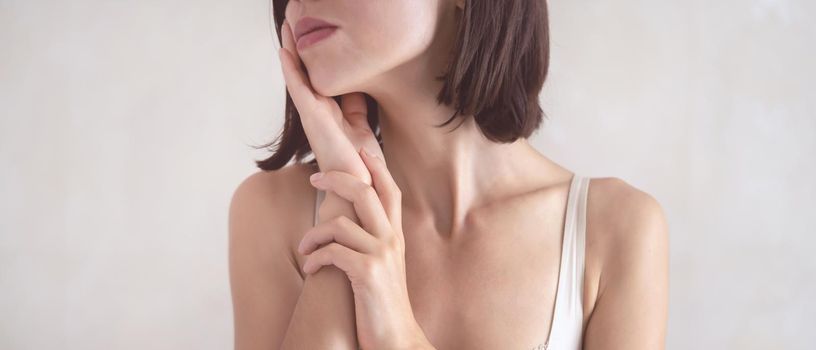 A young girl touches her delicate, clean, moisturized face skin with her hands, a woman takes care of the health and beauty of her body in the bathroom.