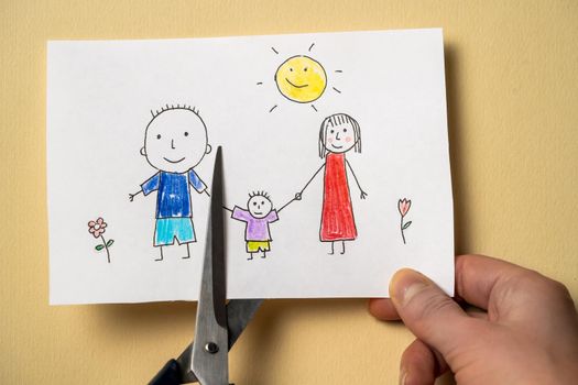 Child's drawing, which depicts mom, dad and child, is cut with scissors. Scissors cuts off Dad in the drawing depicting a happy family. Divorce, difficulties in relationships, problems with the child.