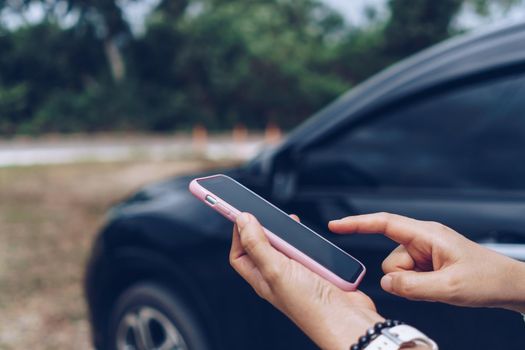 Woman hand using smartphone to do work business, social network, communication in front of car background.