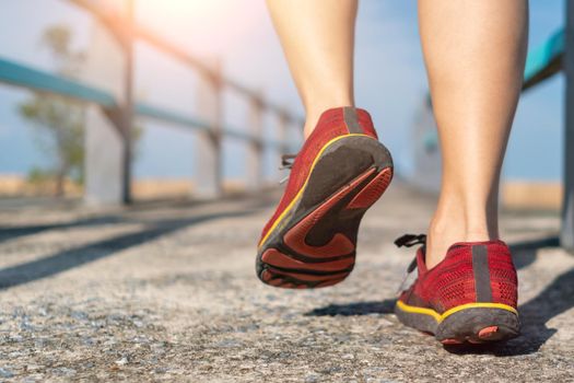 On a green background, a woman walks and runs while wearing running shoes. Exercise for health is a notion.