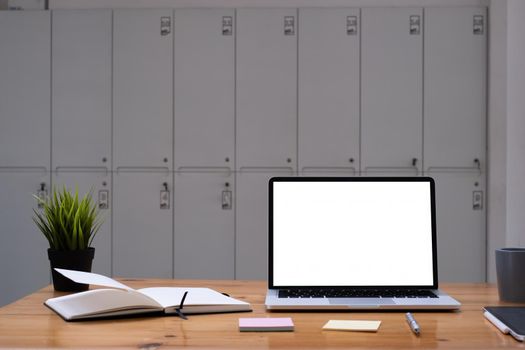 Image of Mock up laptop computer on wooden desk in office. Blank screen for your advertising.