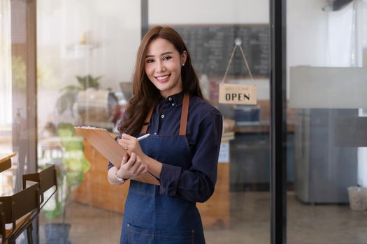 In the background, a successful small business owner stands in front of a counter preparing coffee.