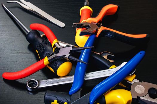 Screwdrivers and pliers, tools on a black wooden table close up