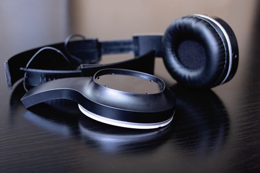 Broken black headphones on a wooden table close up