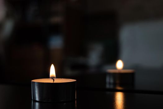 Flame of a small candle in the dark with reflection