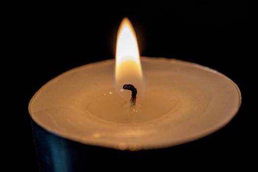 Flame of a small candle in the dark close up