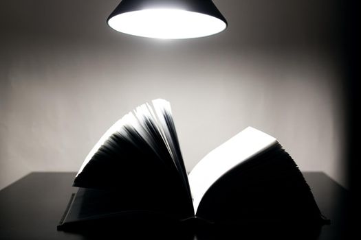 Open book on a table lamp in the dark