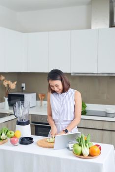 Healthy Asian woman enjoy making green vegetables detox cleanse and green fruit smoothie with blender in kitchen at home. dieting concept.healthy lifestyle