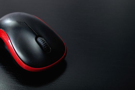 Black computer mouse on a wooden table, copy space