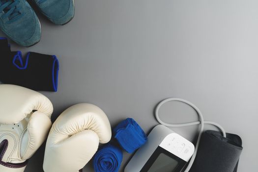 Boxing glove, sphygmomanometer, fitness equipment on gray background with copy space
