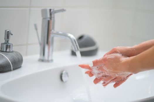 Close-up image of woman washing hands in bathroom.
