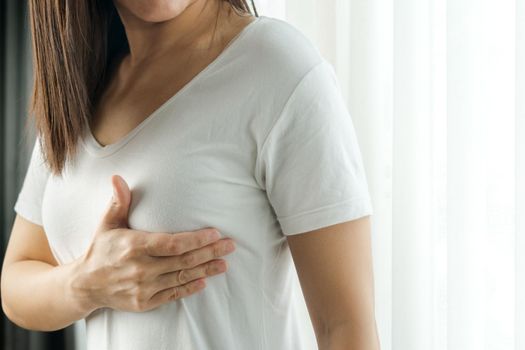 Woman hand checking lumps on her breast for signs of breast cancer. Women healthcare concept.