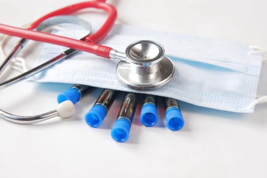 blood test tube, face mask and stethoscope on white ,