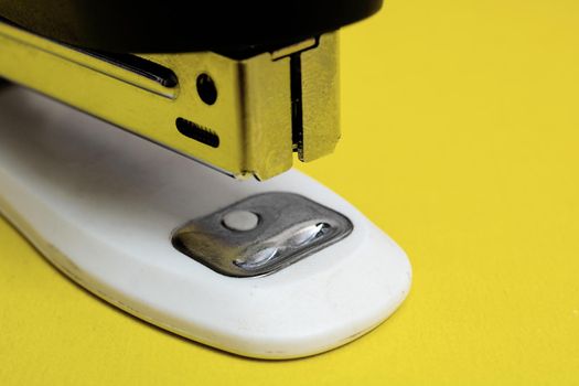 Office stapler on a yellow background close up