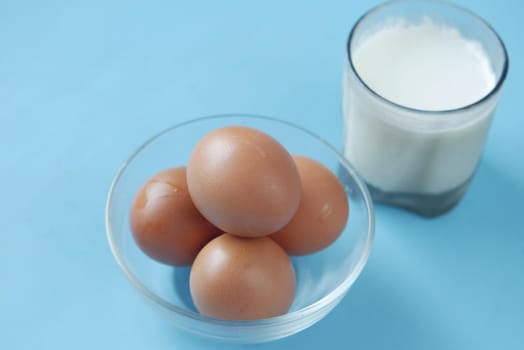 eggs in a bow and a glass of milk on table ,