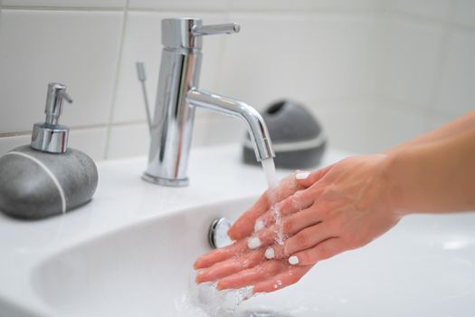 Close-up image of woman washing hands in bathroom.