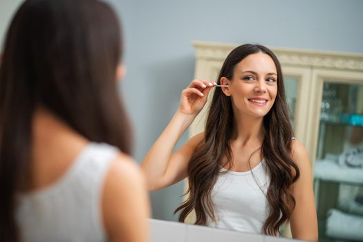 Young woman is cleaning ears in the bathroom.