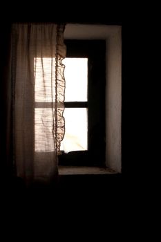 Window of old house with white curtain in Spain. Monochrome picture.