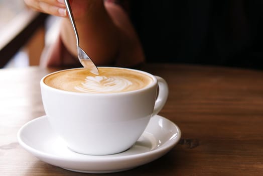 a cup of late coffee with flower shape design on top at cafe .