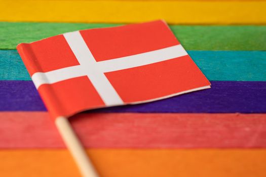 Denmark flag on rainbow background flag symbol of LGBT gay pride month social movement rainbow flag is a symbol of lesbian, gay, bisexual, transgender, human rights, tolerance and peace.