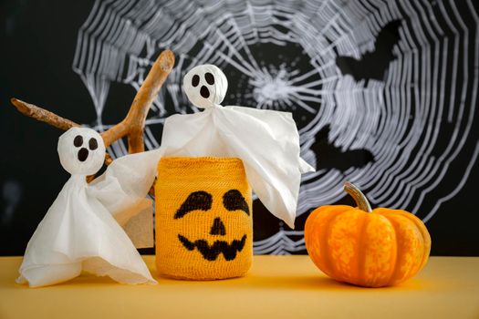 Two ghosts, pumpkin, candlestick with scary Halloween grimace on background of cobweb. Halloween Concept