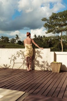 Young woman wearing towel relaxing near swimming pool at exotic location