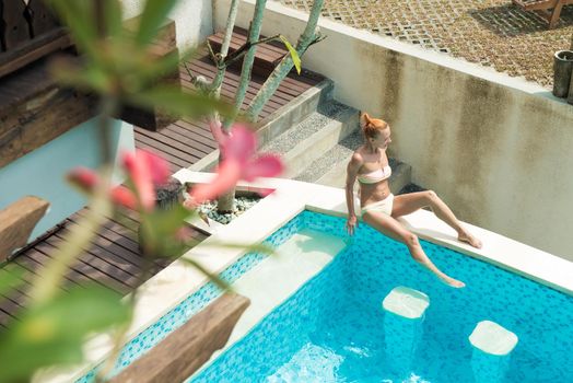 Young woman wearing swimsuit relaxing near swimming pool at exotic location