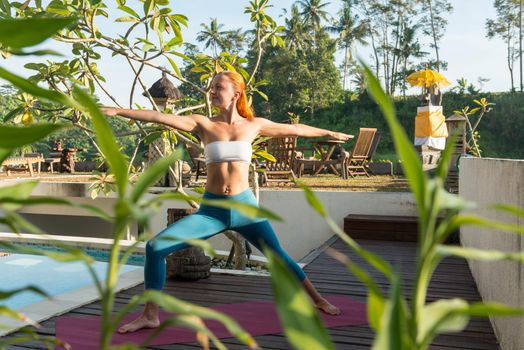 Young woman doing yoga asana in the morning near pool