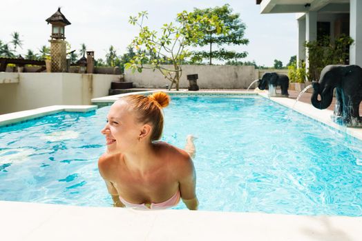 Happy young woman relaxing in beautiful pool