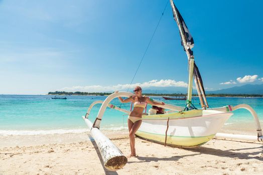 Slim young woman posing with boat at tropical beach