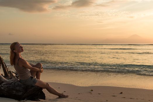 Young woman watching as sun sets over Pacific Ocean