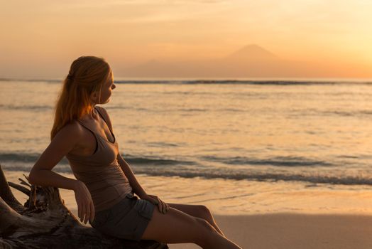 Young woman watching as sun sets over Pacific Ocean