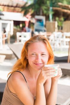 Young woman drinking coffee at beach in the morning