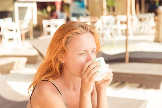 Young woman drinking coffee at beach in the morning