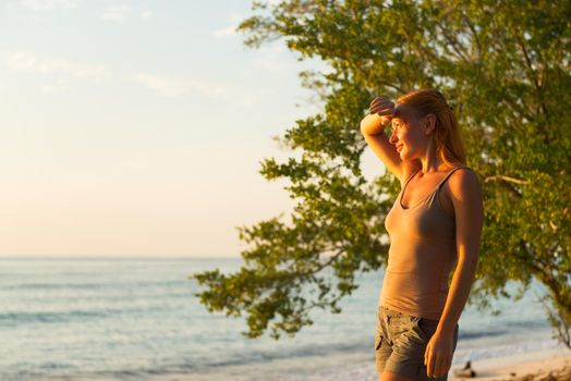 Young woman watching as sun sets over Pacific Ocean