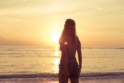 Young woman watching as sun sets over Pacific Ocean