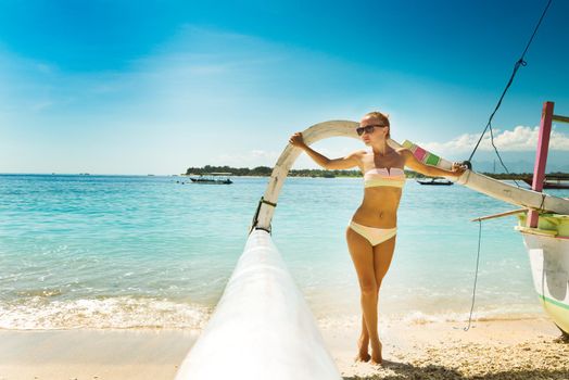 Slim young woman posing with boat at tropical beach