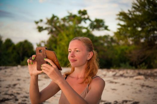 Young woman taking picture with smartphone at beach