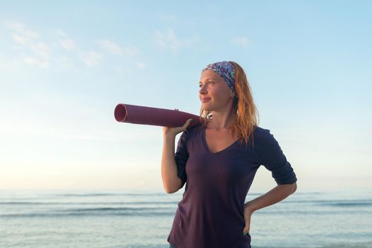 Young woman with long red hair and yoga mat