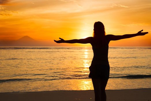 Young woman watching as sun sets over Pacific Ocean