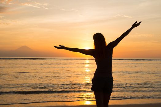 Young woman watching as sun sets over Pacific Ocean