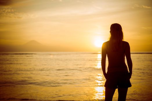 Young woman watching as sun sets over Bali island