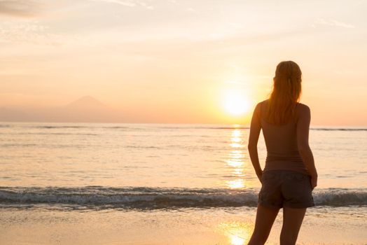 Young woman watching as sun sets over Pacific Ocean