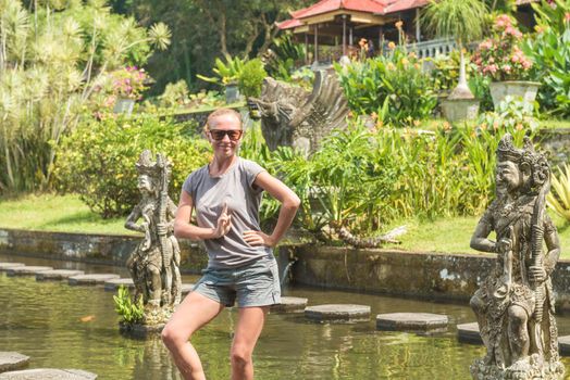 Happy tourist at Tirtagangga water palace with fountains and ponds on Bali, Indonesia