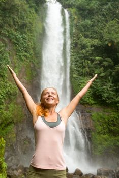 Young woman practicing yoga with waterfall in the background